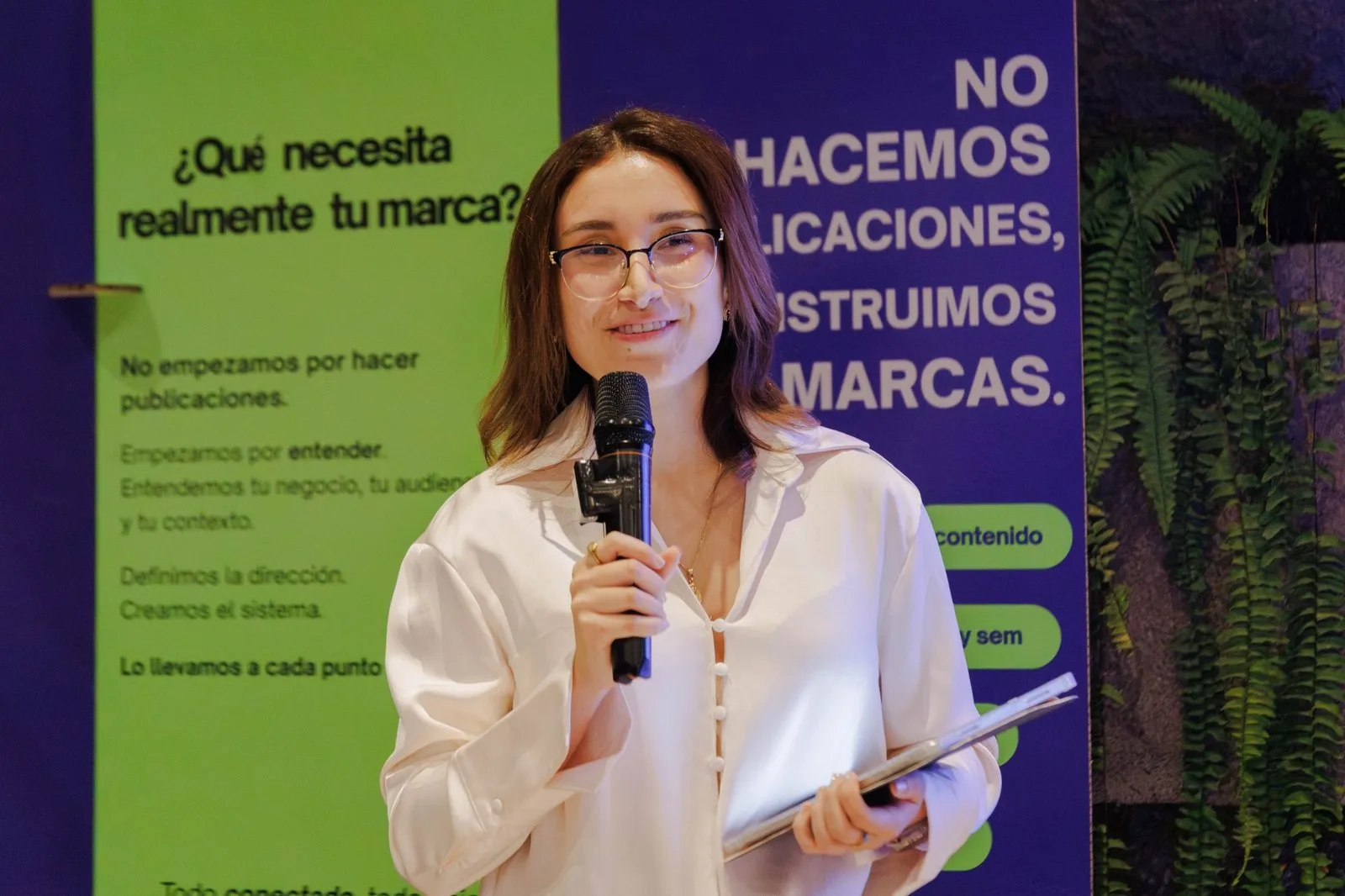 Expositora de TOTEM con micrófono frente al banner «¿Qué necesita realmente tu marca?»